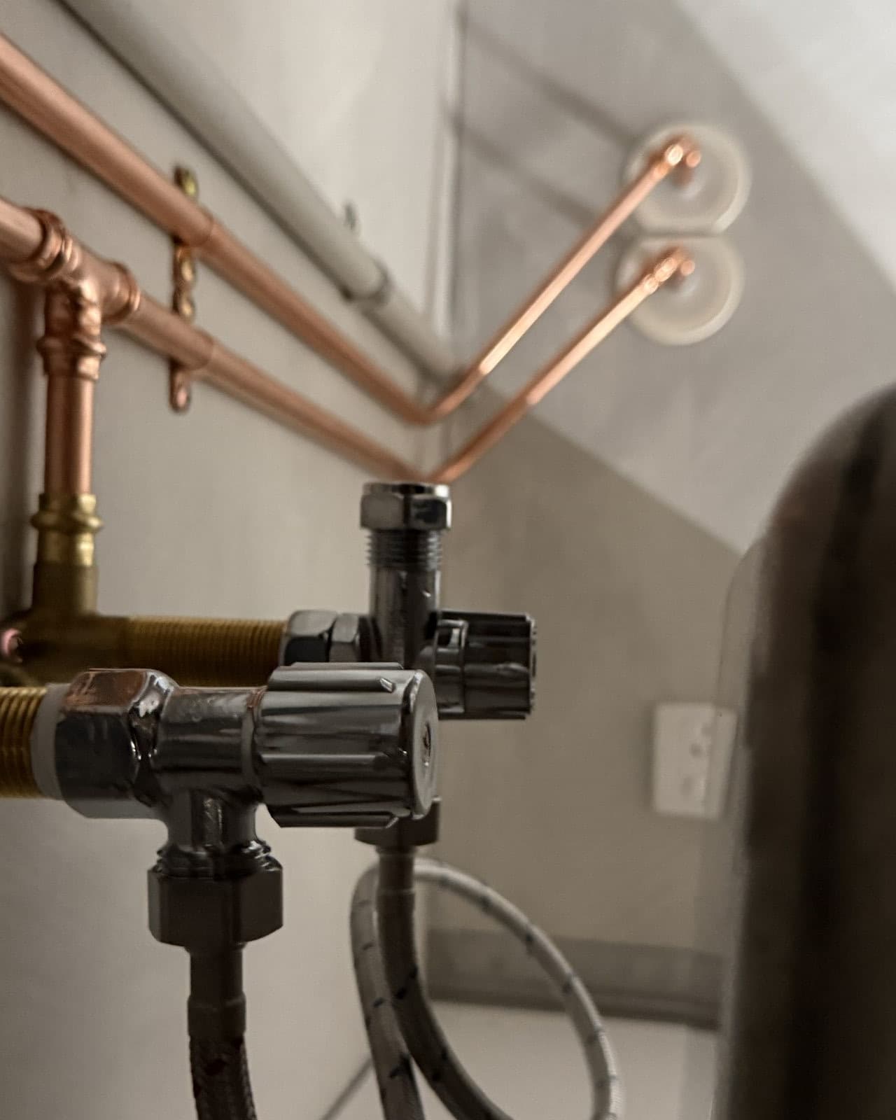 Exposed copper and chrome isolation valves under a commercial cafe sink
